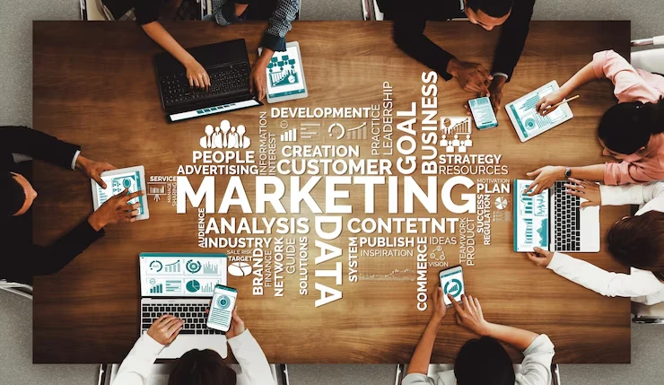 Team of professionals analyzing data and strategy charts on laptops and tablets around a table, representing the work of a digital marketing expert in Thrissur